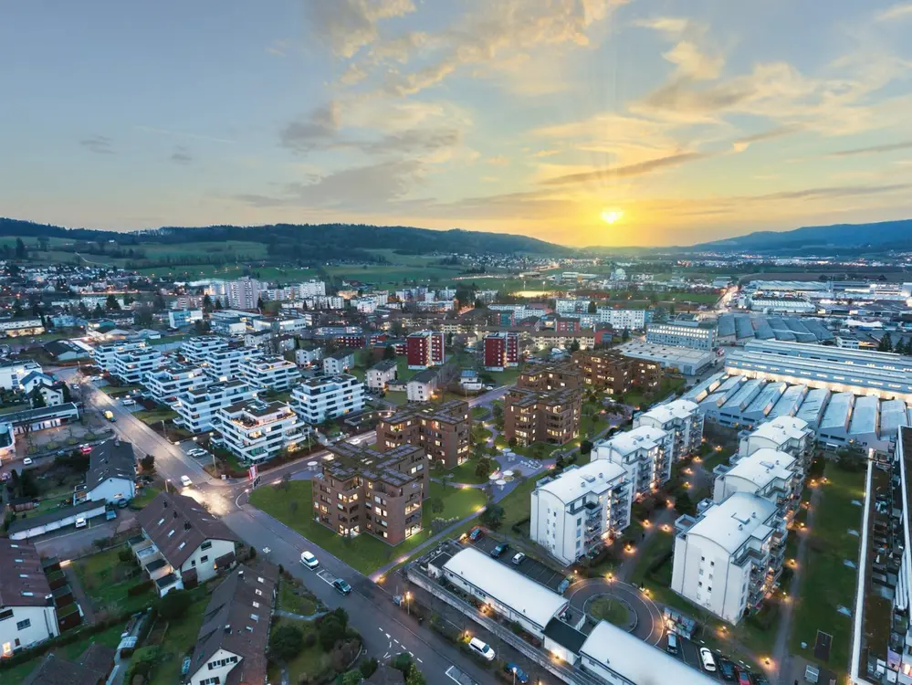 Die Überbauung &quot;Am Riedthof&quot; in Regensdorf, gelegen an der Riedthofstrasse 60-68, ist ein attraktives Wohnangebot, das von der Swiss Life AG aus Zürich realisiert wurde. Sie besteht aus drei Bauteilen, die insgesamt 130 Wohnungen umfassen. Die Wohnungen variieren in der Größe von 1,5- bis 4,5-Zimmerwohnungen und überzeugen durch einen modernen Ausbaustandard​.Die Überbauung befindet sich westlich des Regionalbahnhofs Regensdorf-Watt, angrenzend an die Riedthofstrasse und die Schulstrasse. Das Quartier ist geprägt durch locker angeordnete, durchgrünte Wohnsiedlungen und in westlicher Richtung angrenzende Industriegebiete. Es wurden fünf einzelne Mehrfamilienhäuser mit kreuzförmiger Grundfläche ausgeführt, die teilweise baugleich sind. Alle Gebäude sind oberirdisch fünfgeschossig. Jede Wohnung verfügt mindestens über einen Balkon oder eine Loggia. Im obersten Geschoss springt die Fassade in Teilbereichen nach hinten, womit die Wohnungen dort jeweils eine bis zwei Dachterrassen erhalten. Es gibt auch eine natürlich belüftete Tiefgarage, die durch eine Rampe von der Riedthofstrasse aus erreichbar ist. Neu angelegte Fußwege erschließen die Wohnanlage innerhalb des Gebietes. Die Umgebungsgestaltung besteht aus einer naturnahen Gestaltung und einheimischen, pflegeleichten Pflanzen und Bäumen. Es werden auch Kinderspielbereiche und Aufenthaltsbereiche angeboten​.Die Konstruktion der Gebäude erfolgte in Massivbauweise. Die Fassade erhielt eine Klinkerbekleidung, die durch unterschiedliche Sturz-, Deckenrand- (Rollschicht)- und Brüstungselemente gegliedert wird​.Die Architektur der Überbauung wurde von der Aschwanden Schürer Architekten AG entworfen, während die Erstvermietung durch Livit AG erfolgte. Die Generalunternehmung übernahm Eiffage Suisse AG​​.